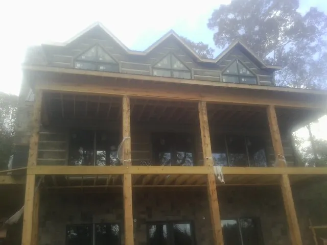 Dormers and porch framing on a large log home under construction — Roof Coating work by our crew in Cornish